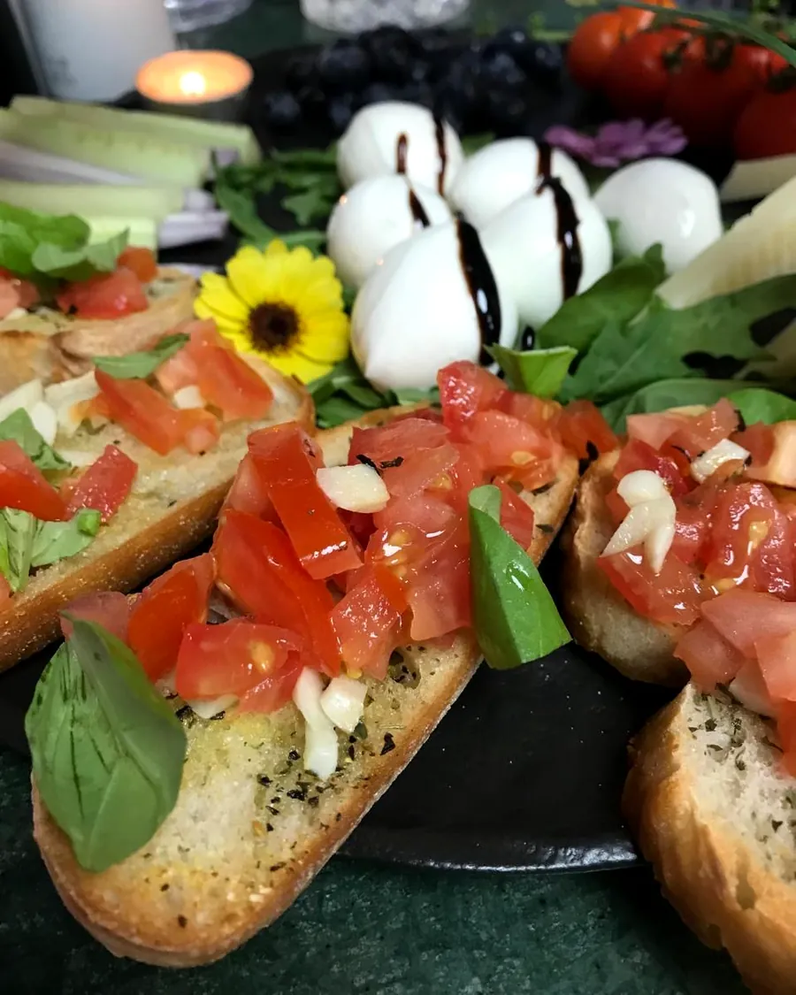 Bruschetta mit Tomaten und Basilikum, dahinter Mozzarella mit Balsamico