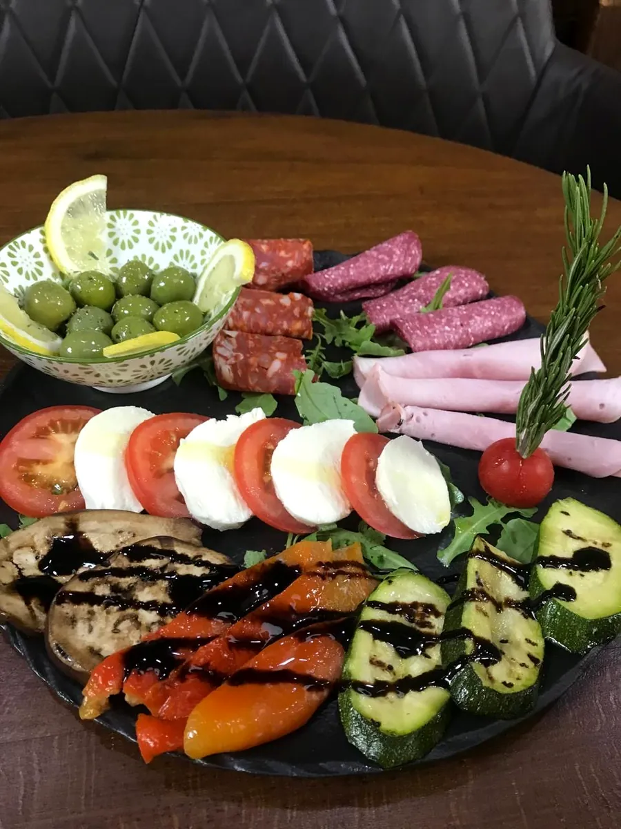 Ganzer Antipasti-Teller mit Oliven, Salami, Schinken, Tomate-Mozzarella und gegrilltem Gemüse
