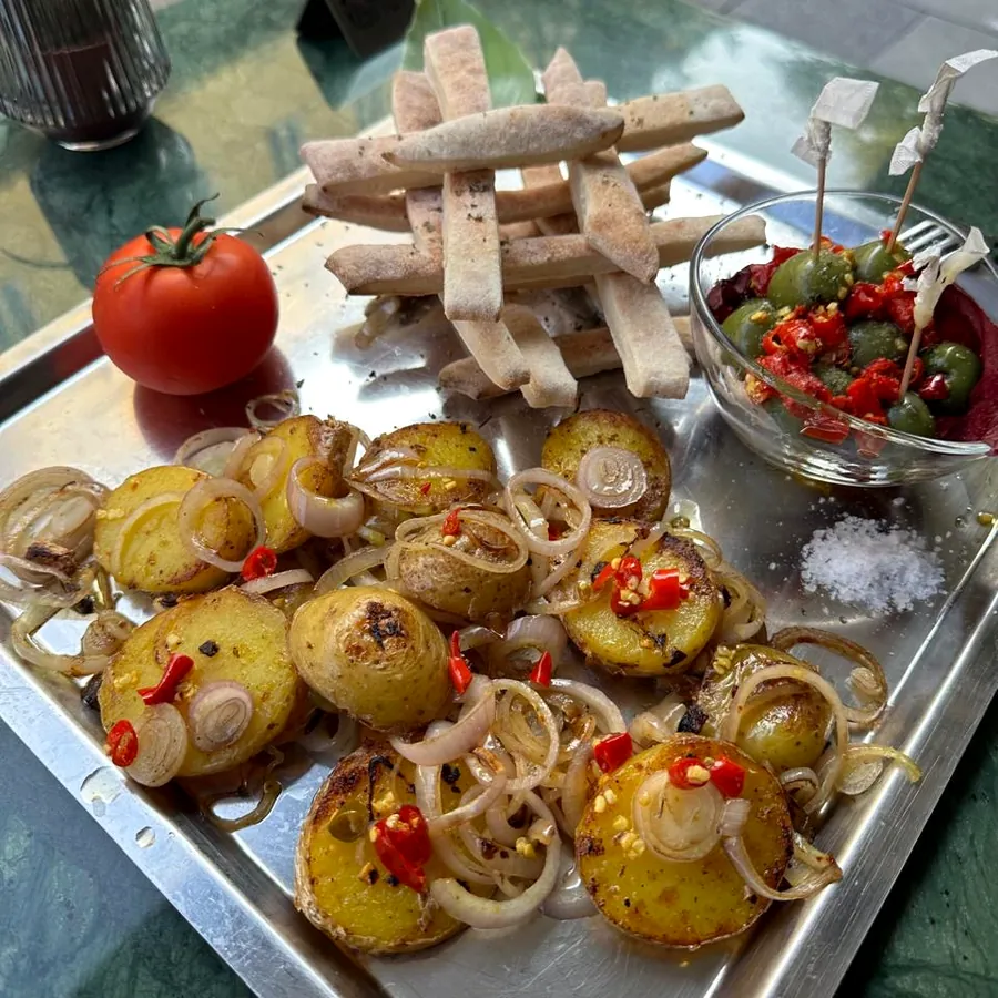 Ofenkartoffeln mit Zwiebeln, Grissini und Oliven auf dem Marmortisch draußen