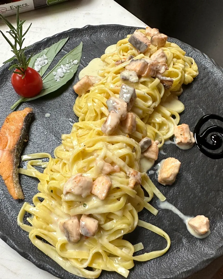 Tagliolini in Lachs-Sahnesauce auf schwarzem Teller